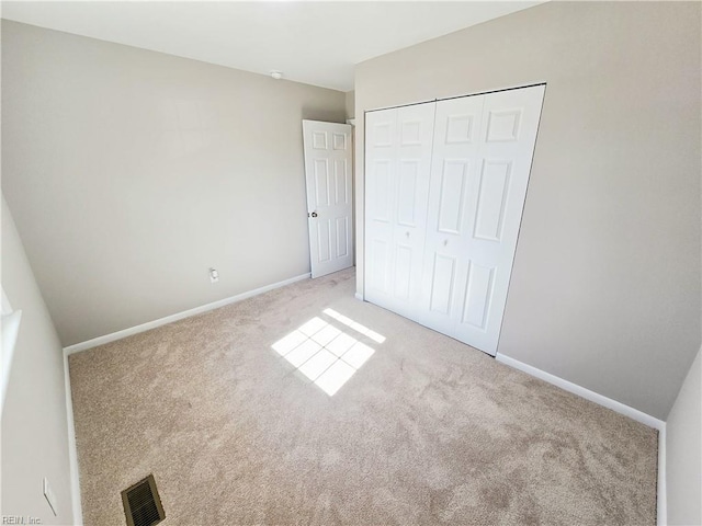 unfurnished bedroom featuring light colored carpet and a closet