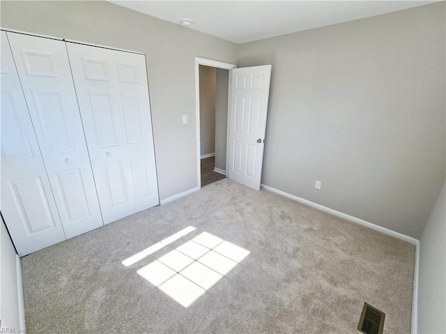 unfurnished bedroom featuring light colored carpet and a closet