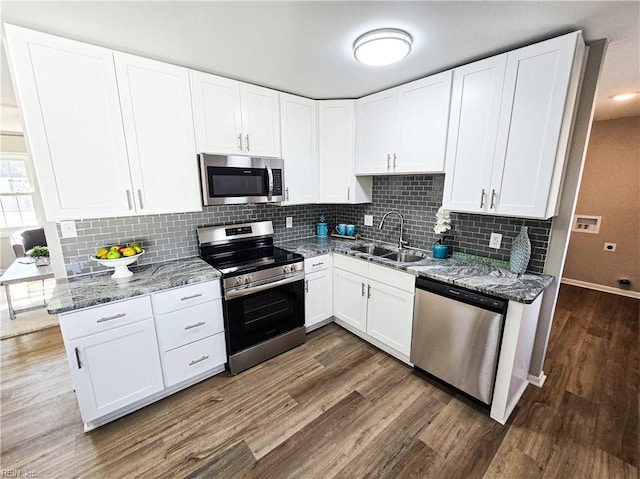 kitchen with sink, stone counters, white cabinetry, stainless steel appliances, and dark hardwood / wood-style flooring