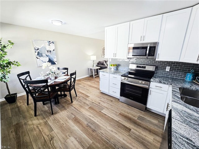 kitchen featuring appliances with stainless steel finishes, dark stone counters, and white cabinets