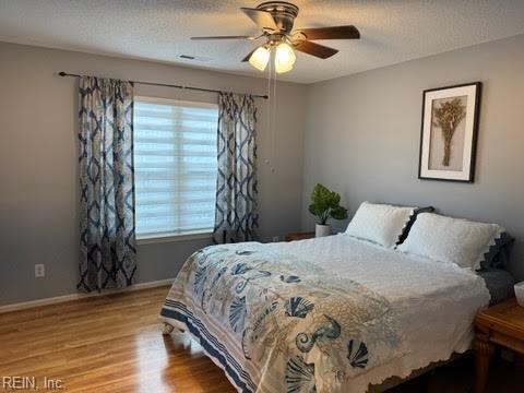 bedroom with ceiling fan, a textured ceiling, and light wood-type flooring