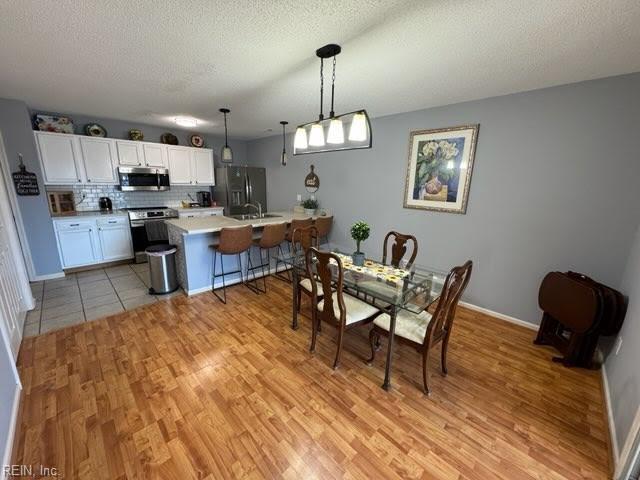 dining area featuring sink, light hardwood / wood-style flooring, and a textured ceiling