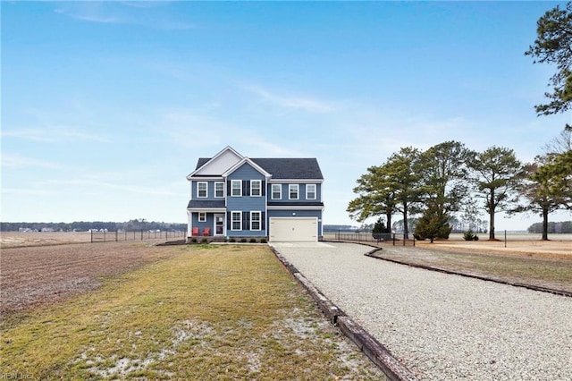 view of front of home with a garage, a rural view, and a front yard