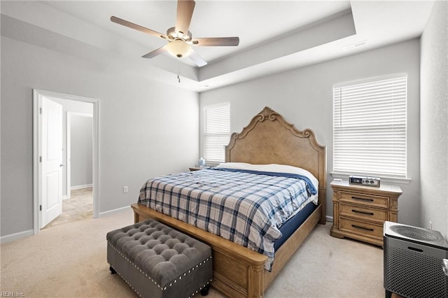 bedroom featuring light carpet, a raised ceiling, and ceiling fan