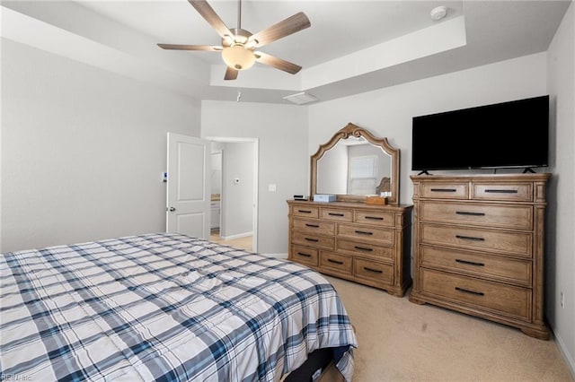 carpeted bedroom featuring a raised ceiling and ceiling fan