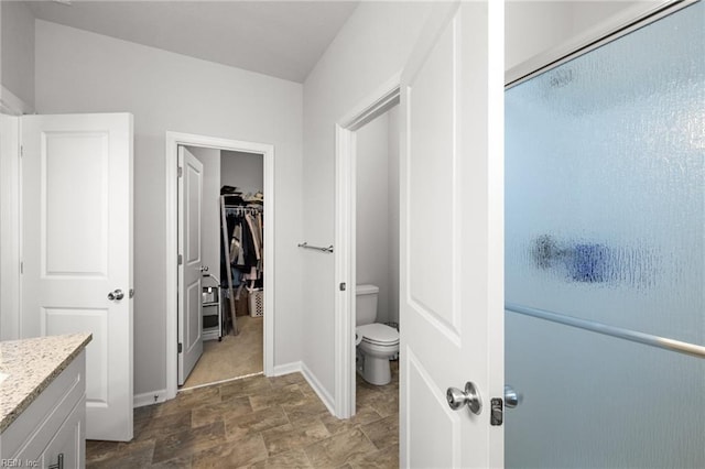 bathroom with vanity, a shower with door, and toilet