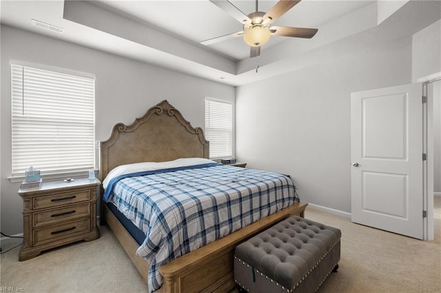 carpeted bedroom featuring a raised ceiling and ceiling fan