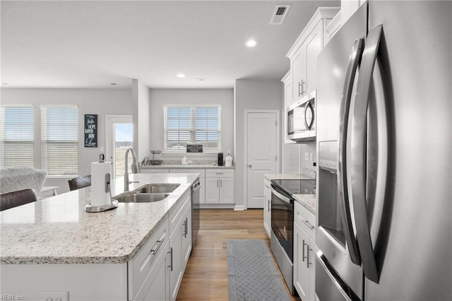 kitchen featuring white cabinetry, sink, a center island with sink, and appliances with stainless steel finishes