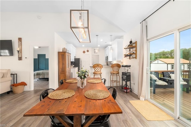 dining room with high vaulted ceiling, a notable chandelier, and light hardwood / wood-style floors