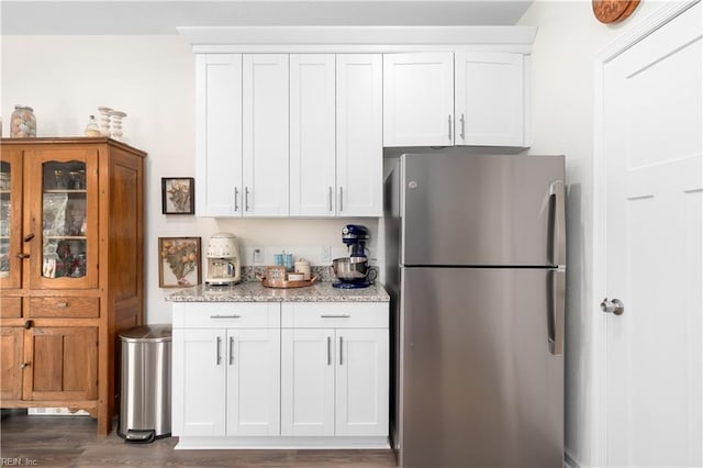 kitchen with stainless steel refrigerator, white cabinetry, dark hardwood / wood-style floors, and light stone countertops