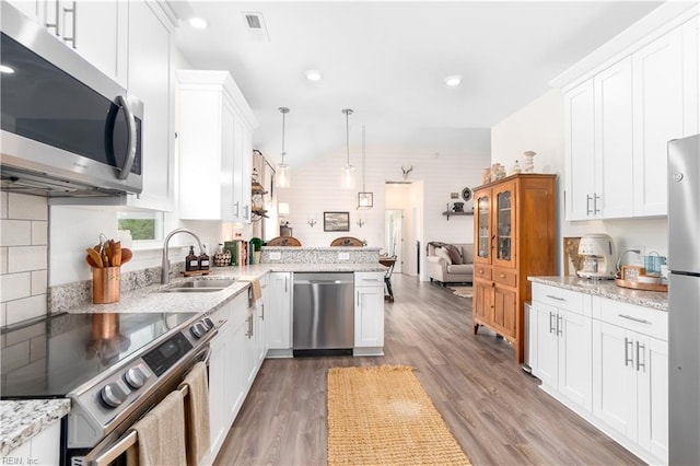 kitchen featuring pendant lighting, sink, white cabinetry, stainless steel appliances, and kitchen peninsula