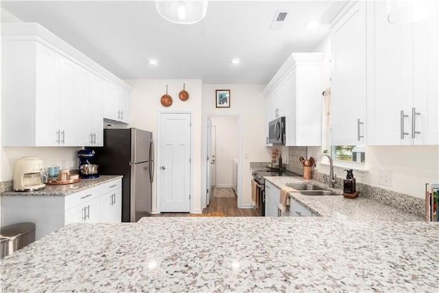 kitchen with white cabinetry, appliances with stainless steel finishes, sink, and kitchen peninsula