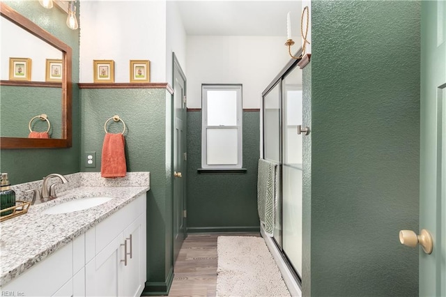 bathroom featuring vanity, hardwood / wood-style floors, and a shower with door