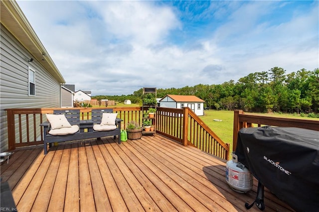 wooden deck featuring a storage shed, a yard, and a grill