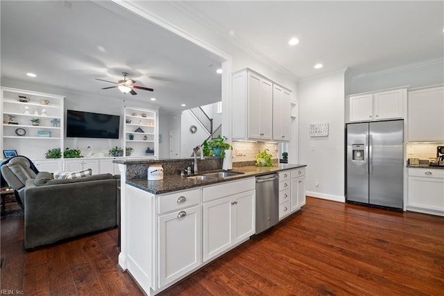 kitchen with sink, appliances with stainless steel finishes, ornamental molding, white cabinets, and dark stone counters