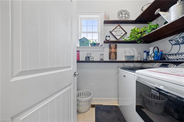 clothes washing area with light tile patterned flooring and separate washer and dryer