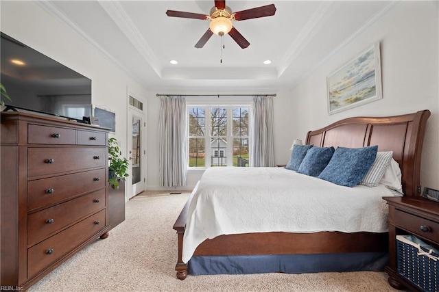 carpeted bedroom with a tray ceiling, ornamental molding, and ceiling fan