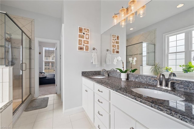 bathroom featuring tile patterned flooring, vanity, a wealth of natural light, and a shower with door