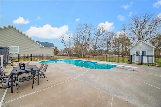 view of swimming pool with a patio, a diving board, and an outbuilding