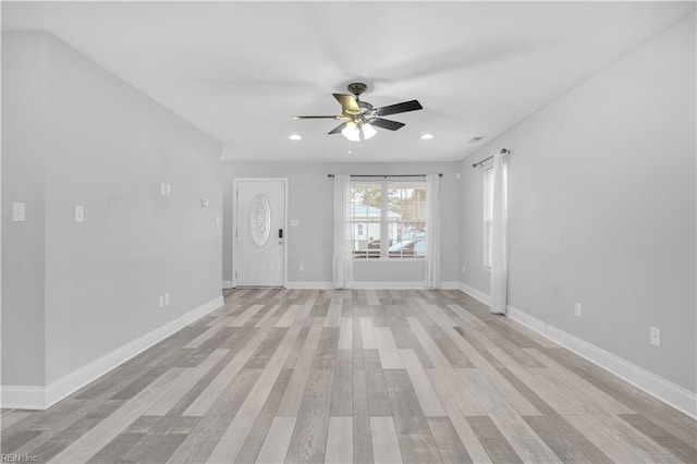 unfurnished room with ceiling fan, a barn door, and light hardwood / wood-style flooring