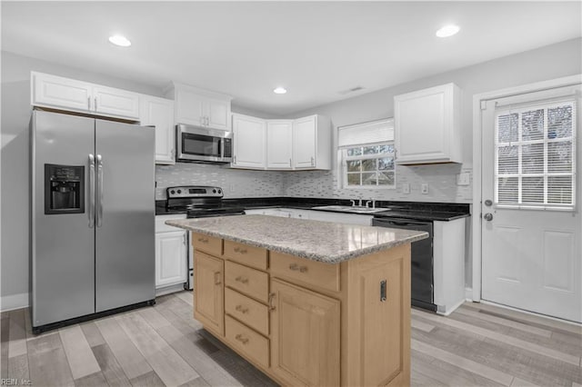 kitchen featuring stainless steel appliances, light wood-type flooring, a kitchen island, and white cabinets