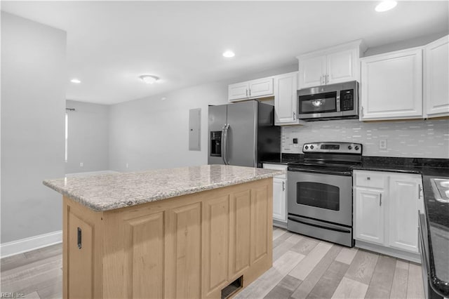 kitchen with a center island, dark stone countertops, white cabinets, stainless steel appliances, and backsplash