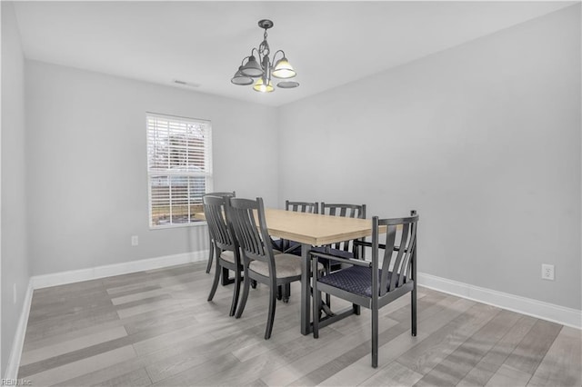 dining space with light hardwood / wood-style flooring and a chandelier