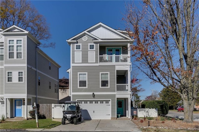 coastal inspired home featuring driveway, a balcony, fence, and board and batten siding