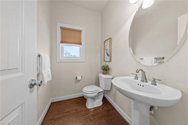 half bathroom with a sink, wood finished floors, toilet, and baseboards