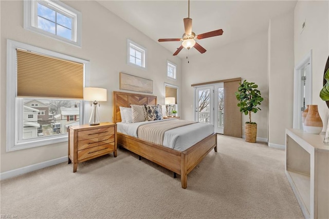 bedroom featuring light carpet, baseboards, a ceiling fan, a towering ceiling, and access to exterior