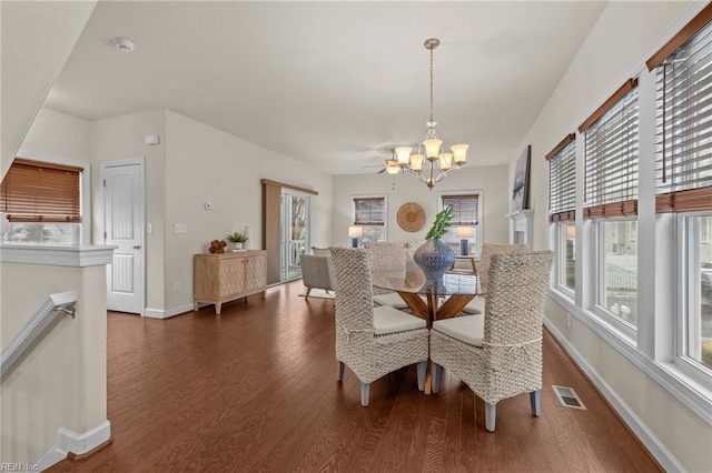 dining space with dark wood-style flooring, visible vents, a notable chandelier, and baseboards