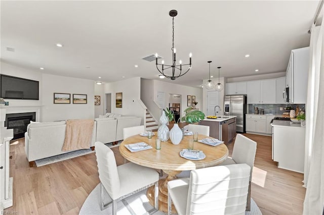 129 Getty Rd, Suffolk, VA 23434 - dining area with a chandelier, light wood finished floors, stairs, recessed lighting, and a glass covered fireplace