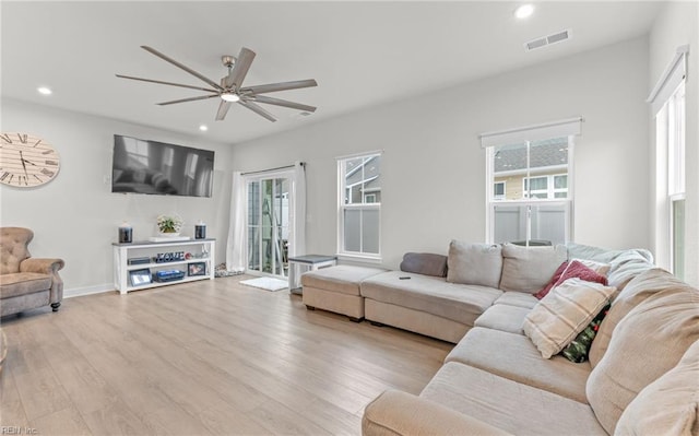 living room featuring ceiling fan, plenty of natural light, and light wood-type flooring