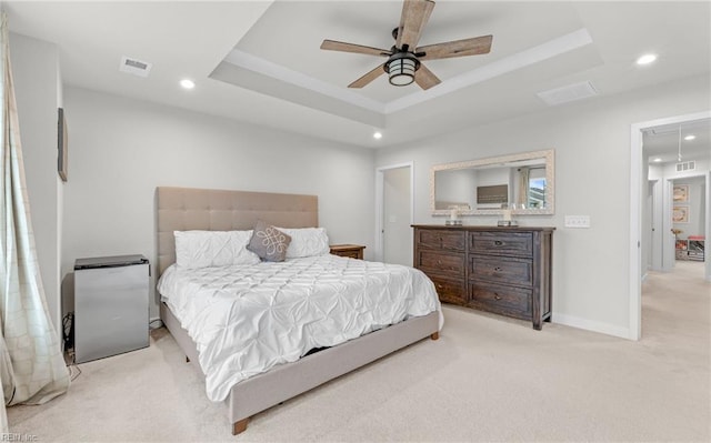 bedroom featuring light colored carpet, a raised ceiling, and ceiling fan