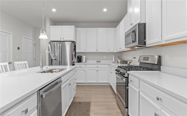 kitchen with stainless steel appliances, sink, white cabinets, and decorative light fixtures