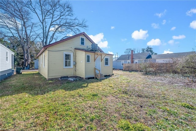 back of property featuring a yard and central AC