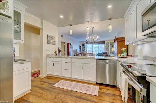 kitchen with crown molding, appliances with stainless steel finishes, light hardwood / wood-style floors, white cabinets, and decorative light fixtures