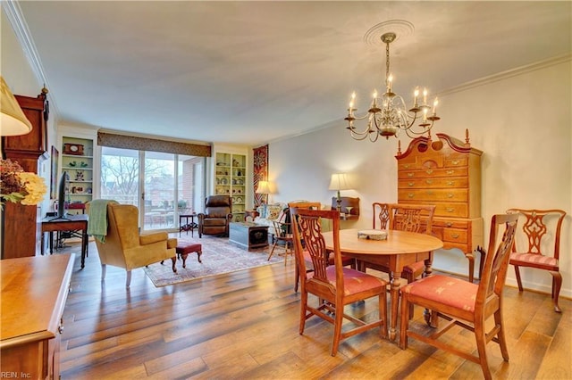 dining area featuring a notable chandelier, ornamental molding, built in features, and light wood-type flooring