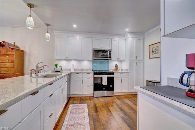 kitchen with appliances with stainless steel finishes, sink, pendant lighting, and white cabinets