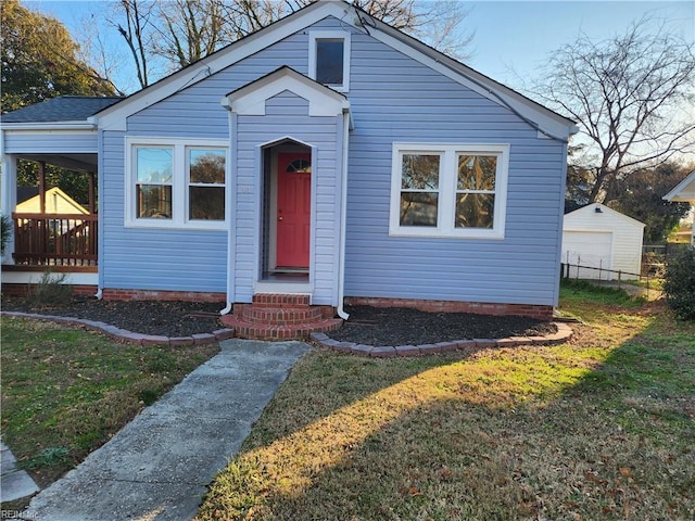 bungalow-style home featuring a garage, an outbuilding, and a front lawn