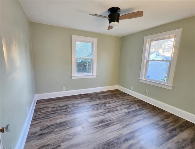 spare room with dark wood-type flooring, a wealth of natural light, and ceiling fan