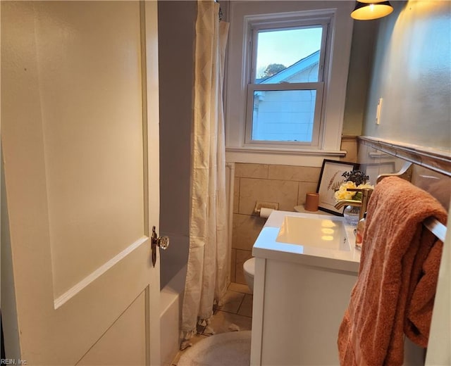 full bathroom with vanity, toilet, tile walls, and shower / bath combo