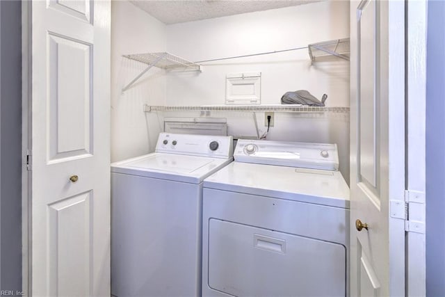 laundry area featuring washing machine and clothes dryer and a textured ceiling