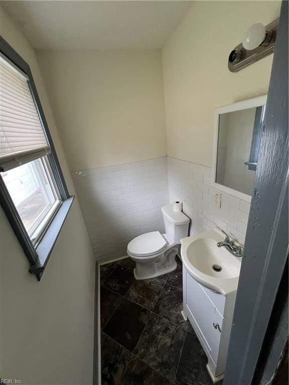 bathroom featuring vanity, toilet, and tile walls