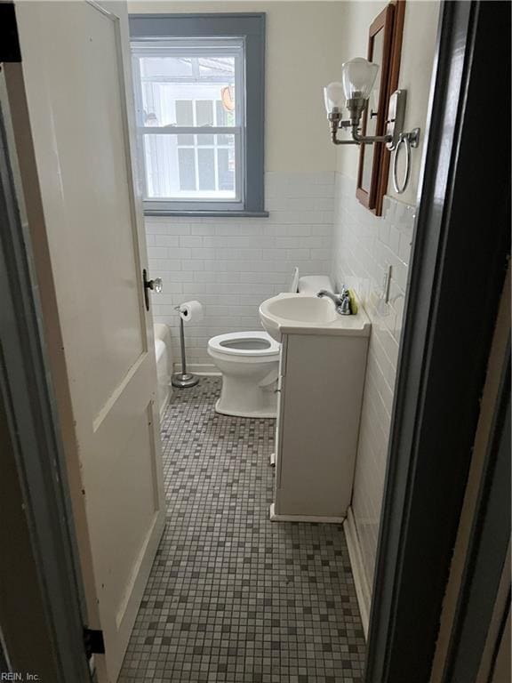 bathroom featuring tile patterned flooring, vanity, tile walls, and toilet