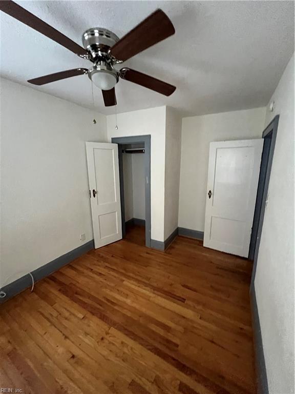 unfurnished bedroom with ceiling fan, dark hardwood / wood-style floors, a closet, and a textured ceiling