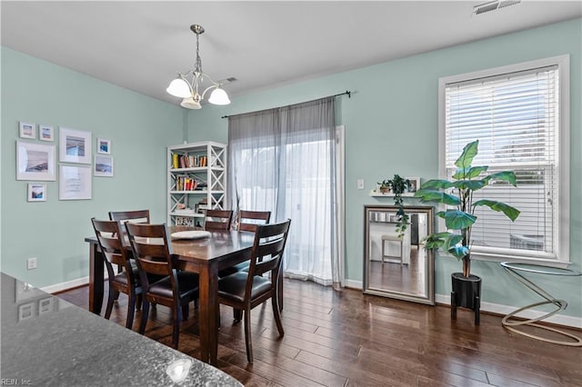 dining room with dark hardwood / wood-style flooring and a chandelier