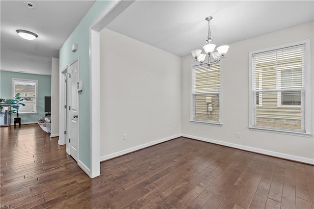 spare room with dark wood-type flooring and a chandelier