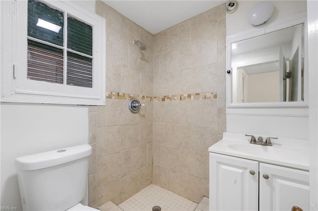 bathroom with vanity, tiled shower, and toilet