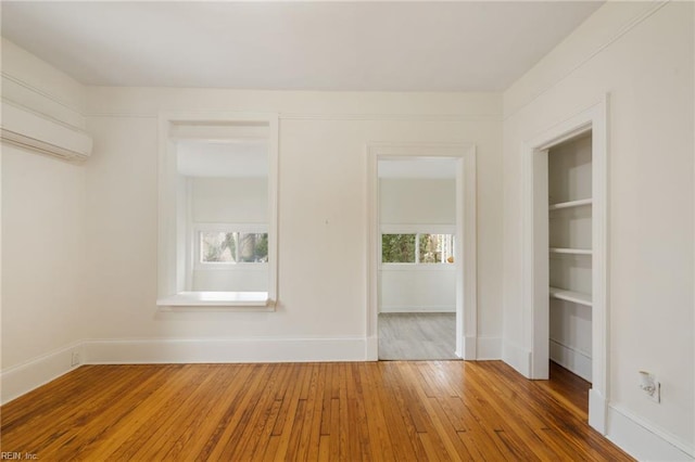 spare room with wood-type flooring and an AC wall unit